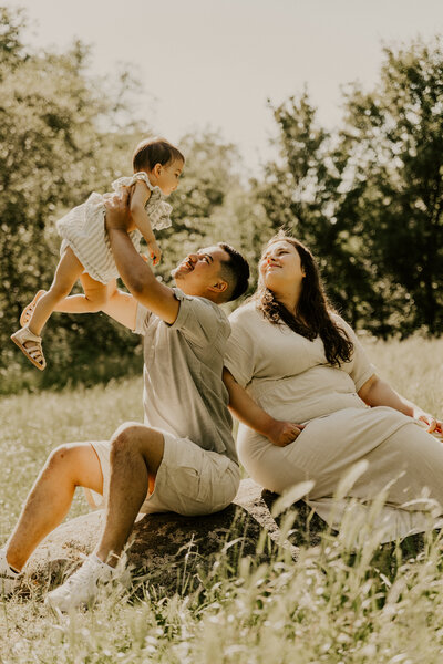 Femme enceinte en robe blanche reposant sa tête sur l'épaule de son partenaire, capturée par Laura, photographe grossesse en Vendée.