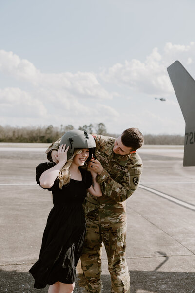 Soldier places his helmet playfully on his significant other.