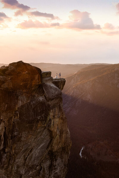 A bride and groom stand at taft point in yosemite.