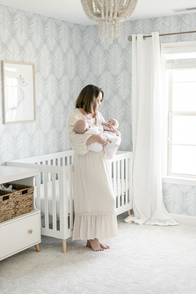 A mother holds her twin newborns in a luxury nursery by Nashville Newborn Photographer Kristie Lloyd