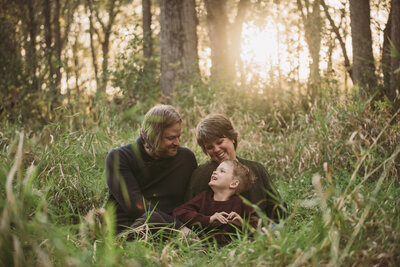 family of three sitting in grass