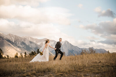 bride and groom walking across mountain scape