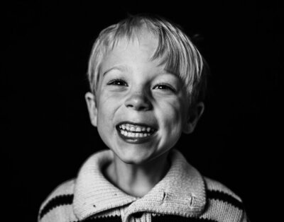 A little boy's eye's twinkle and he smiles broadly as Kate Simpson of Kate Simpson Photography interacts with him on his school picture day.