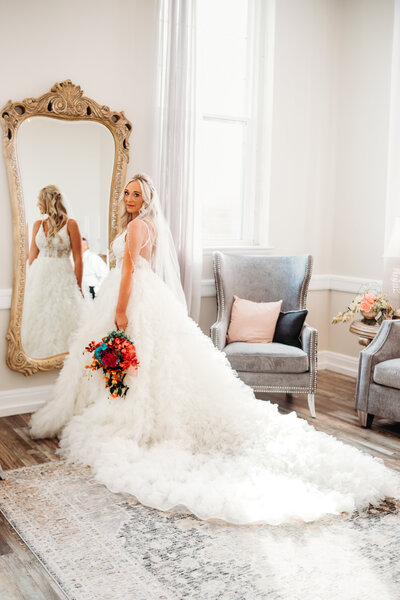 bride standing in front of the mirror holding flowers