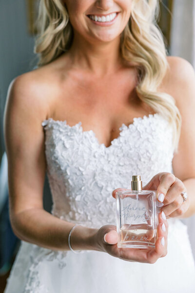 Smiling bride holding engraved perfume bottle with her name