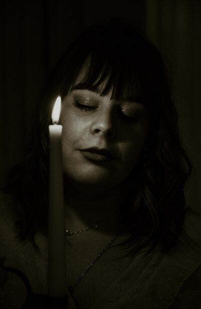 author holds a candle up to her face and closes her eyes 