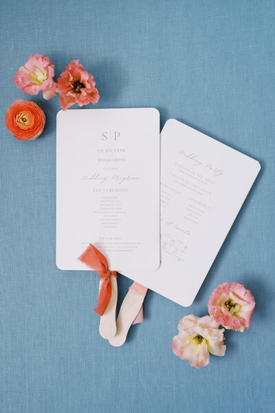 Flat lay of wedding stationery and flowers on a blue background