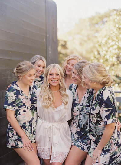 Tropical navy, pink and green bridesmaid pajamas surrounding a bride in her sophisticated wedding dress