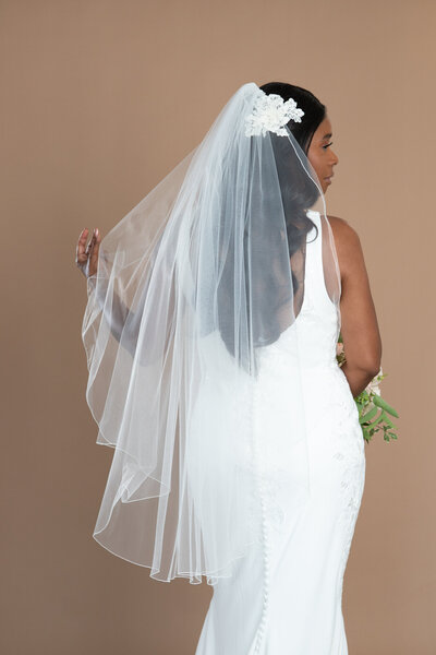 Bride wearing a fingertip length veil with serged edge and holding a white and blush bouquet