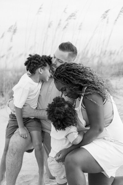 Mom and Dad lovingly embracing their young boys at Barony Beach Club in Hilton Head, SC with Hilton Head Photographer, Lamp and Light Photography.