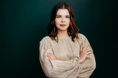 Woman posing for a headshot with a green backdrop.