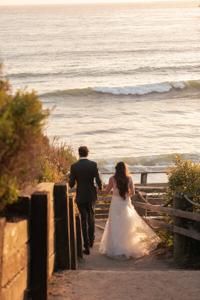 candid Wedding Photos of couple holding hands with ocean in Pismo Beach at Dolphin Bay Resort & Spa