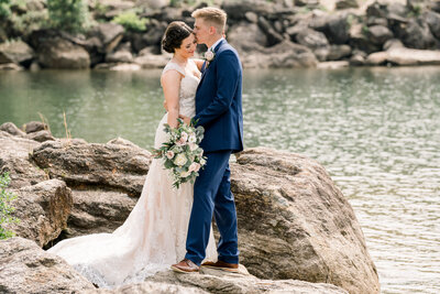 Bride and Groom standing on rocks in the lake at Lake Lanier Islands
