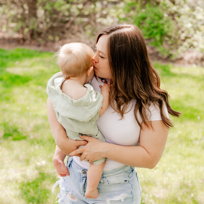 Mother holding and kissing infant's head.