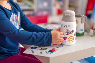 Child decorating  a Luua water bottle with custom stickers in Weston.