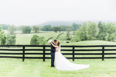 Married couple kissing with the rolling hills of the Marriott Ranch in the background.