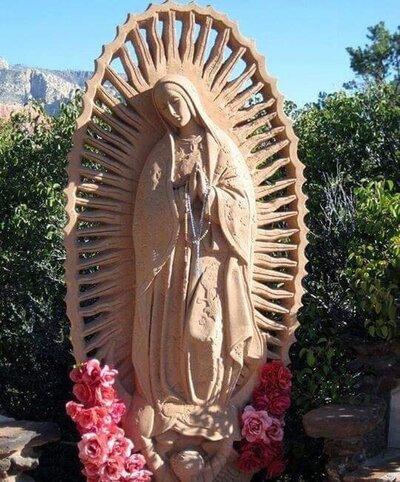 image of tan  Mother Mary statue in a garden with pink flowers