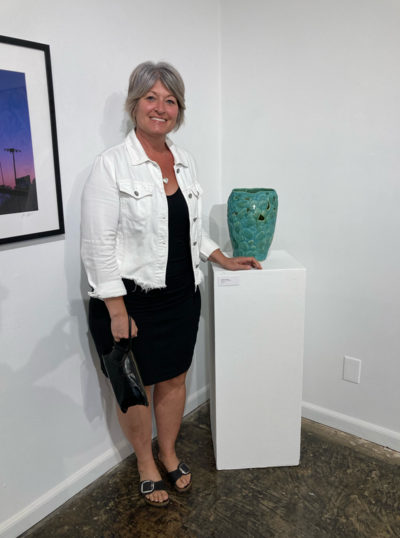 Jill stands beside her teal vase with relief detailing inside of The Studios of Key West