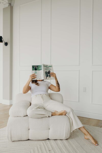 Brand and Web Design for Mindful Entrepreneurs Sitting on a white couch reading a gardening book