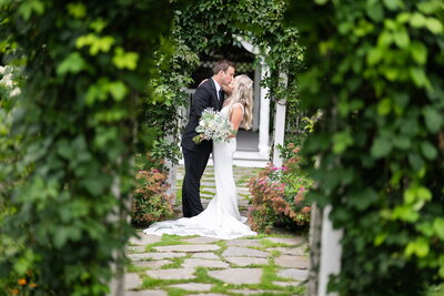 Garden wedding ceremony couple kissing under archway
