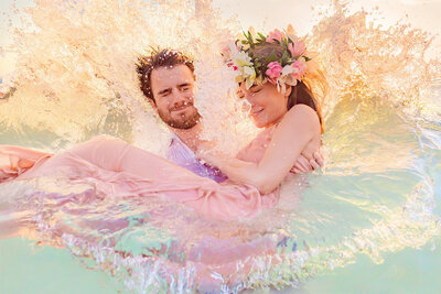 maui engagement portrait couple splashing in the colorful ocean in maui