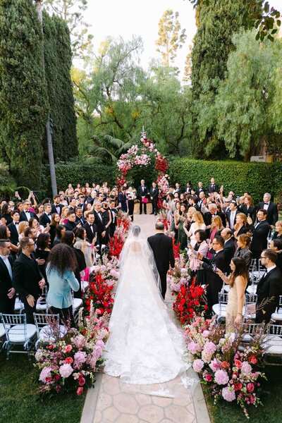 Drone image of bride walking down the aisle with her dad at the gardens of Beverly Hills hotel.