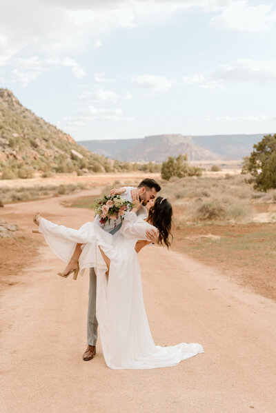bride and groom holding each other as the sun glows on their faces with snow capped mountains behind them in Salt Lake City