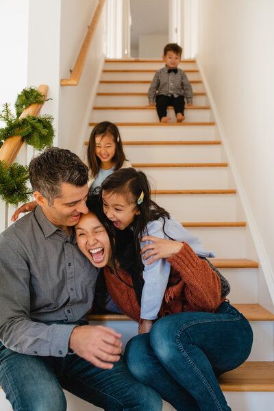 Family Photographer, a young family laughs together as the play on the stairs