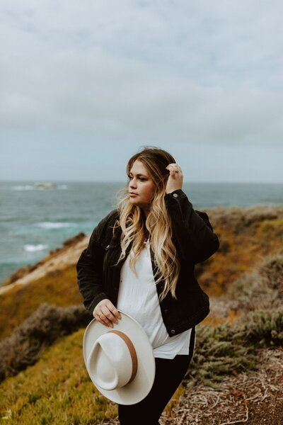 woman holding hair and hat