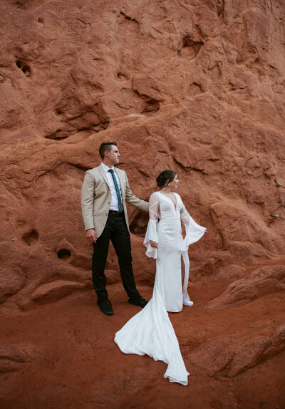 A couple standing among red rock formations during their Colorado elopement