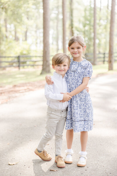 Young brother and sister standing with their arms around each other and smiling. -Greenville SC Photographer