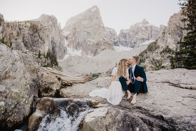young bride with caramel hair poses with her wedding bouquet looking down at the florals, captured by Jackson Hole wedding photographer