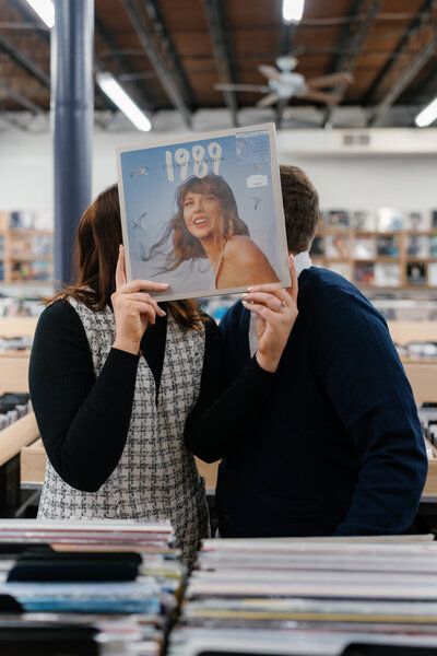 A couple holding up a vinyl over their faces