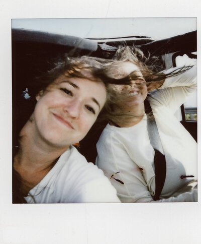 Polaroid selfie of JayneMayAgnes and a friend in a jeep with the top off and hair blowing everywhere