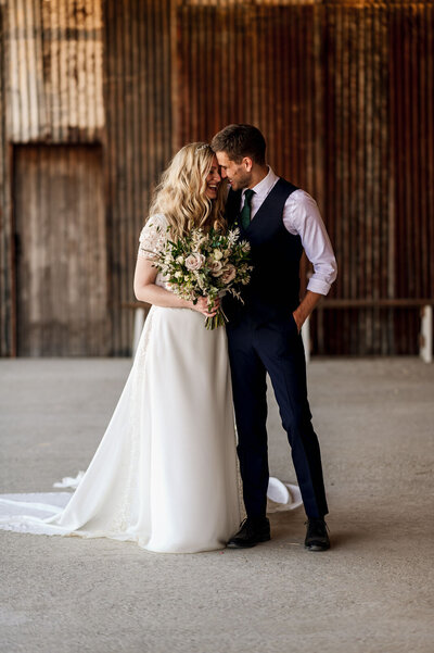 Groom giving bride a piggyback ride at outdoor reception