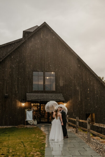 bride and groom kissing in the rain in front of the mountain top inn in vermont