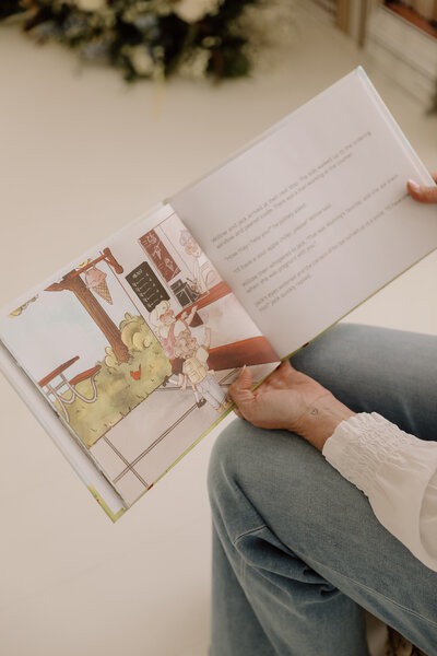 A children's illustrated book being held open by the author