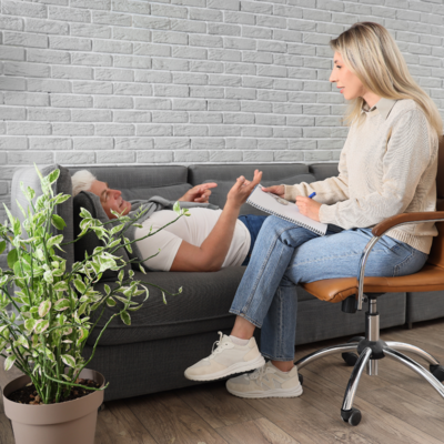 Female therapist talking to male client laying on couch.  Hypnotherapist, hypnotherapy, rapid transformational therapy, RTT rapid transformational therapist, hypnotherapy for infertility, hypnotherapy for fertility, hypnobirthing, hypnotherapy for birth