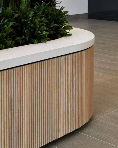 A large indoor planter encircled by fluted wood panels