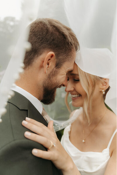 Newlyweds embrace under wedding veil at Minnesota farm wedding venue
