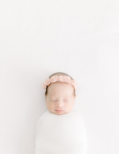 Newborn photo of a baby girl wrapped up laying on a bed in a photo studio Las Vegas