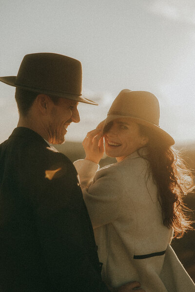 Playful sunset shot on the Sunshine Coast of a couple at sunset wearing akubra hats by professional engagement photographer