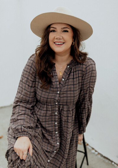 smiling woman wearing a hat in a gray dress
