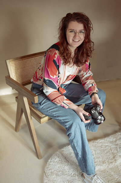 Ilse van Rijssen van ZeimenX Visuals poseert voor een portret foto. Ze zit op een stoel en lacht de camera in.