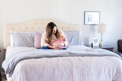 A mom snuggling her newborn daughter in bed.