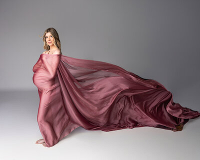 Maternity session in Murrysville pa where mom poses in mauve fabric blowing in the wind portrait.