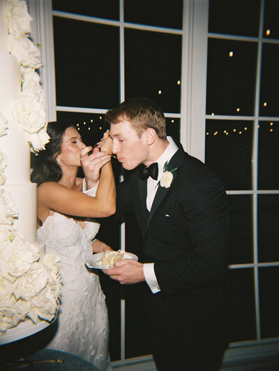 Flash film photo of bride and groom feeding each other a wedding cake