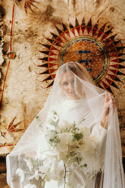 photo of bride wearing bridal gown and veil while holding bridal bouquet taken by Jackson Hole destination wedding photographer