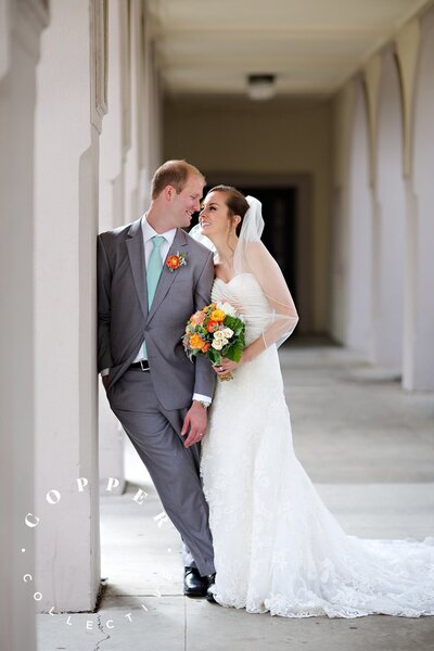 Bride and Groom leaning on tower for their wedding at the Founders Chapel in San Diego