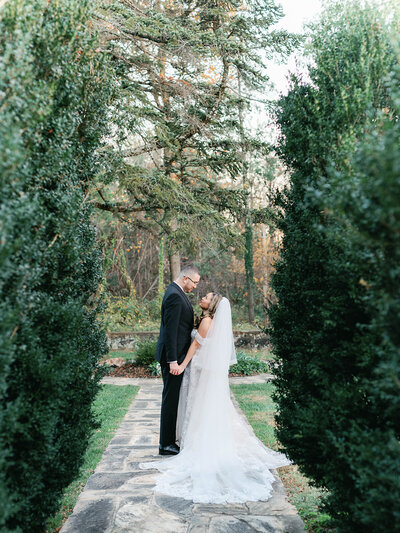 Photo of couple in between tall green hedges